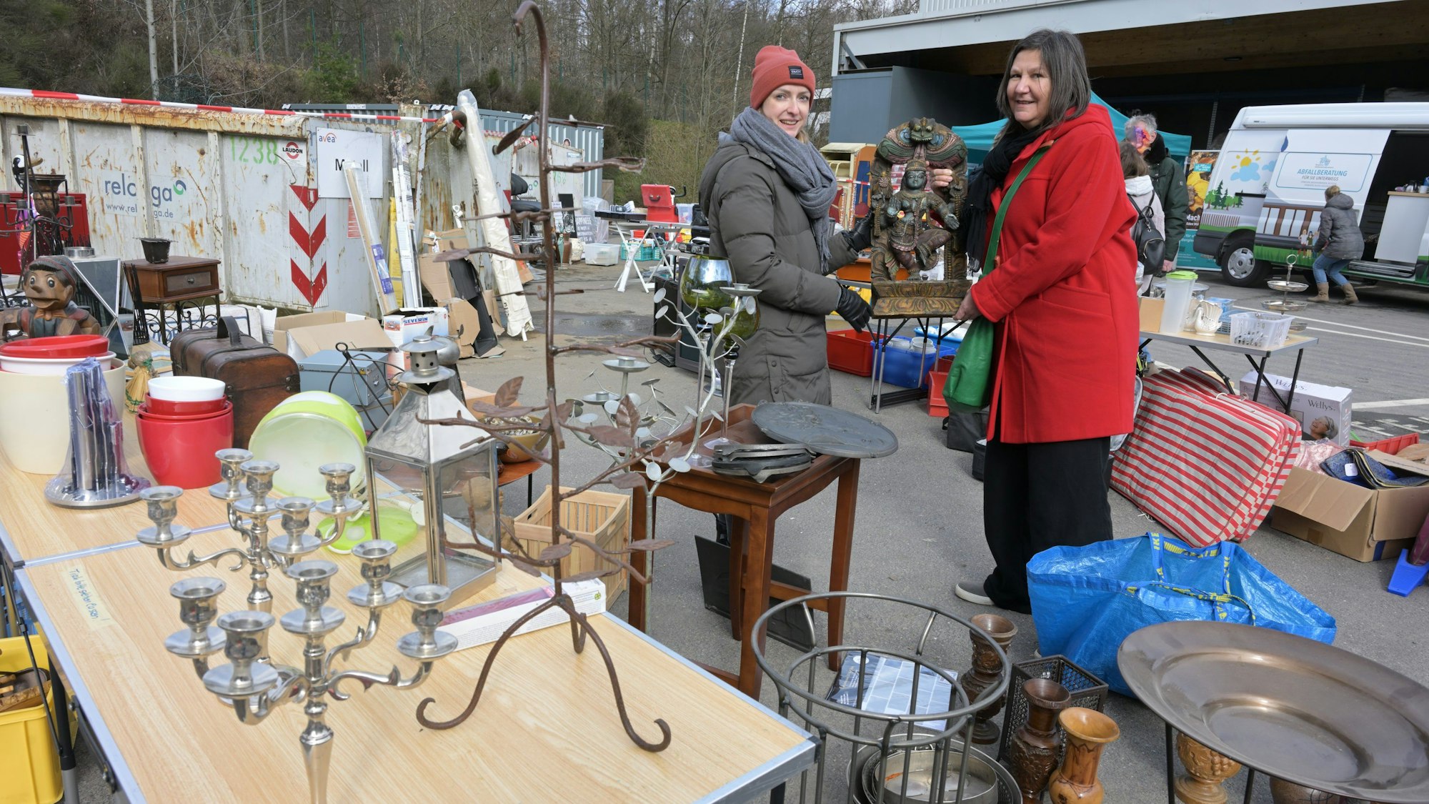 Zwei Frauen halten auf dem Trödelmarkt einen Budda hoch.