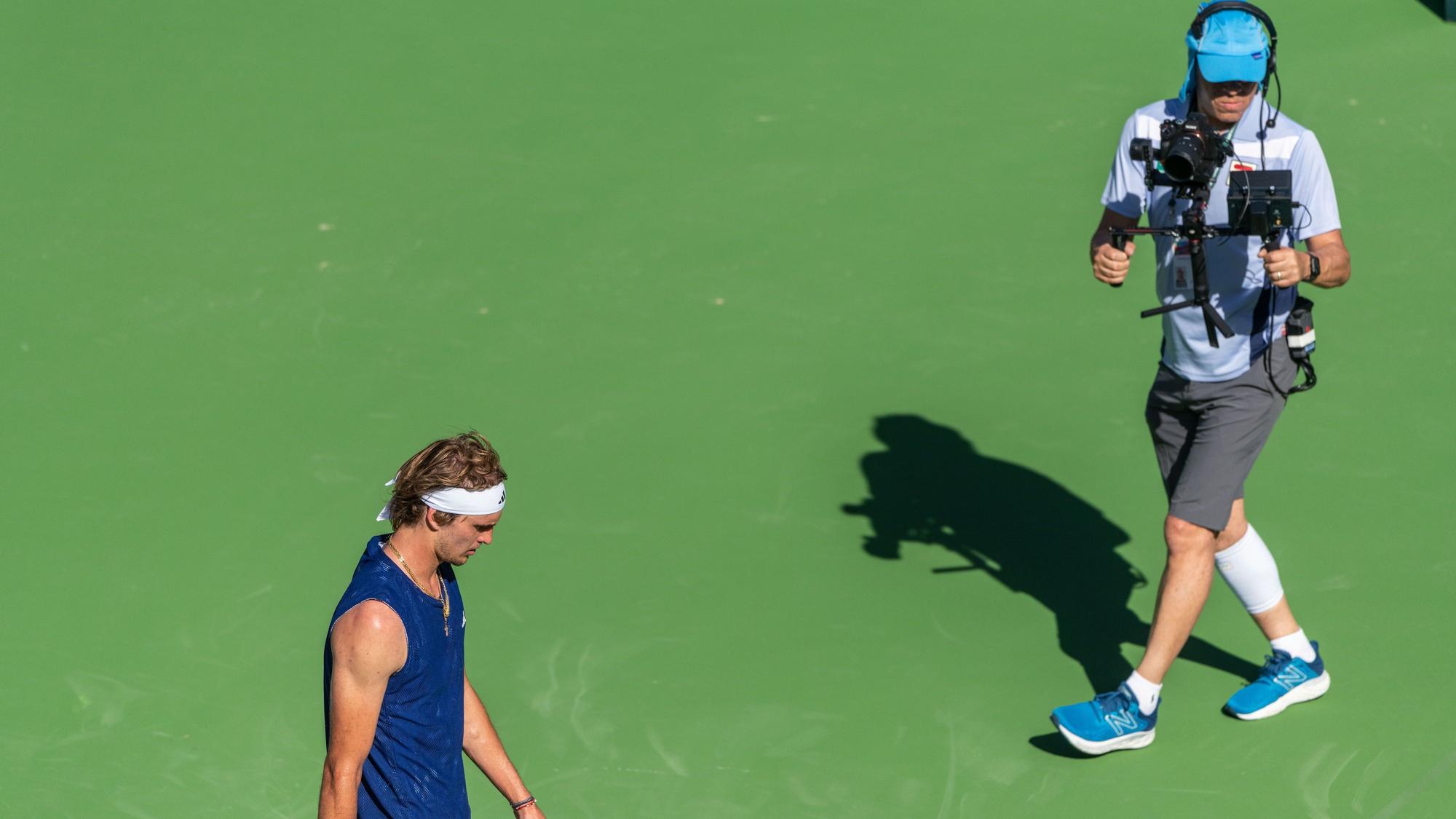 Ein Kameramann filmt Olympiasieger Alexander Zverev auf dem Platz.