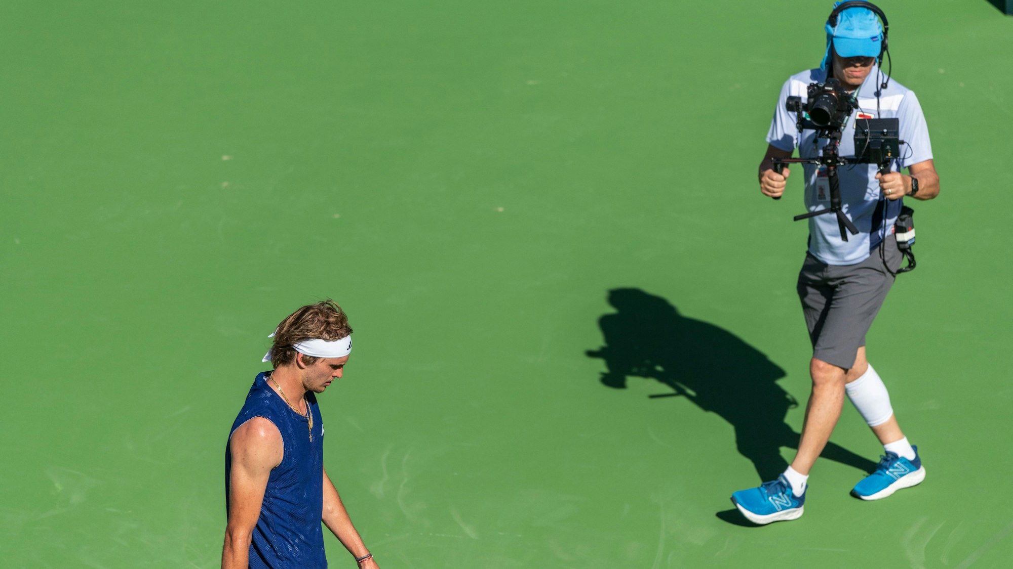 Ein Kameramann filmt Olympiasieger Alexander Zverev auf dem Platz.