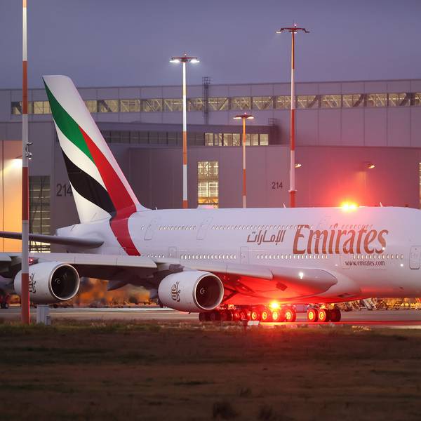 Ein Airbus A380 der arabischen Fluggesellschaft Emirates rollt zur Start- und Landebahn. Im Hintergrund ist ein großer Hangar zu sehen.