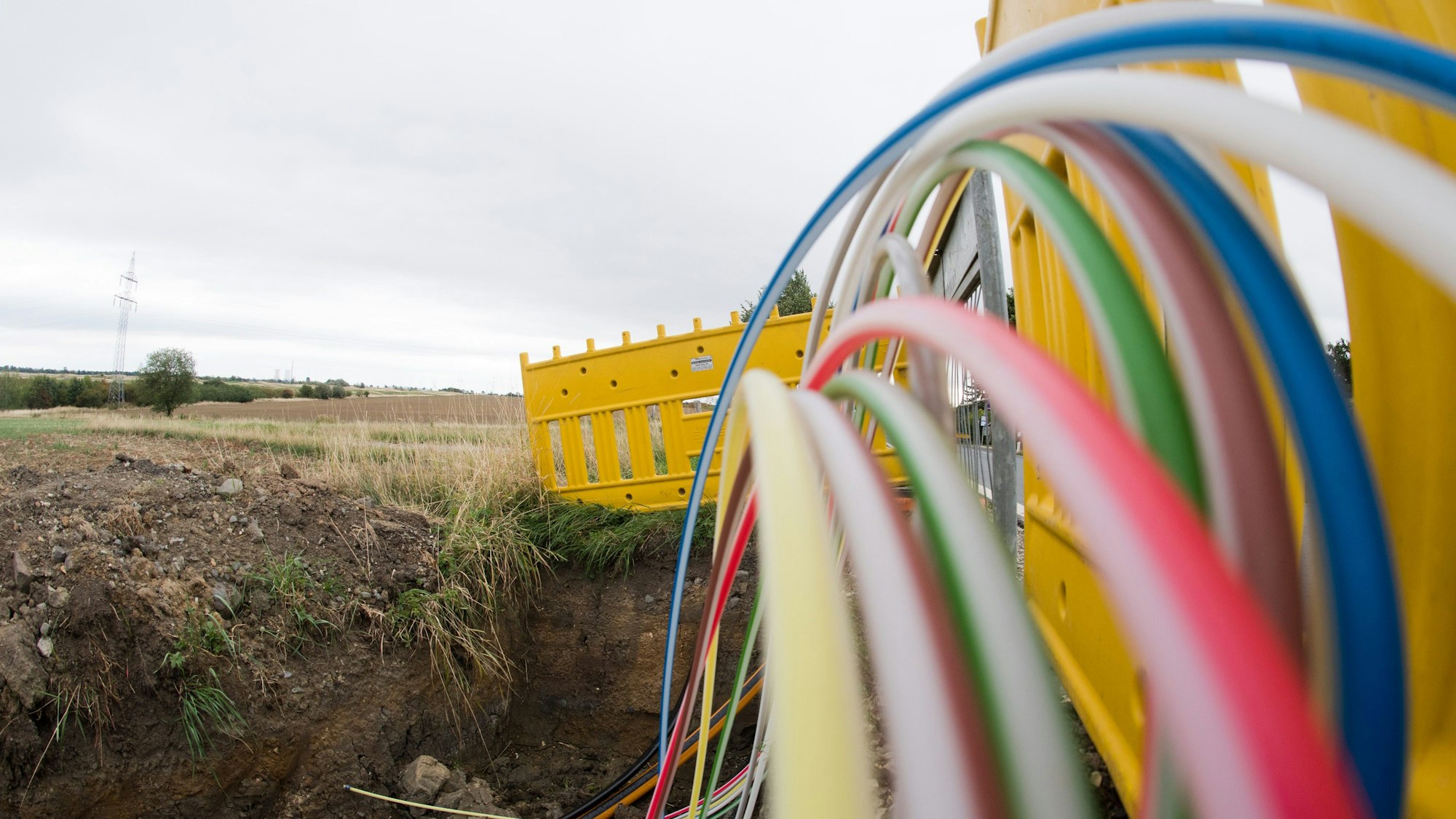 Leerrohre für Glasfaserleitungen für schnelles Internet liegen an einer Landstraße in der Baugrube.