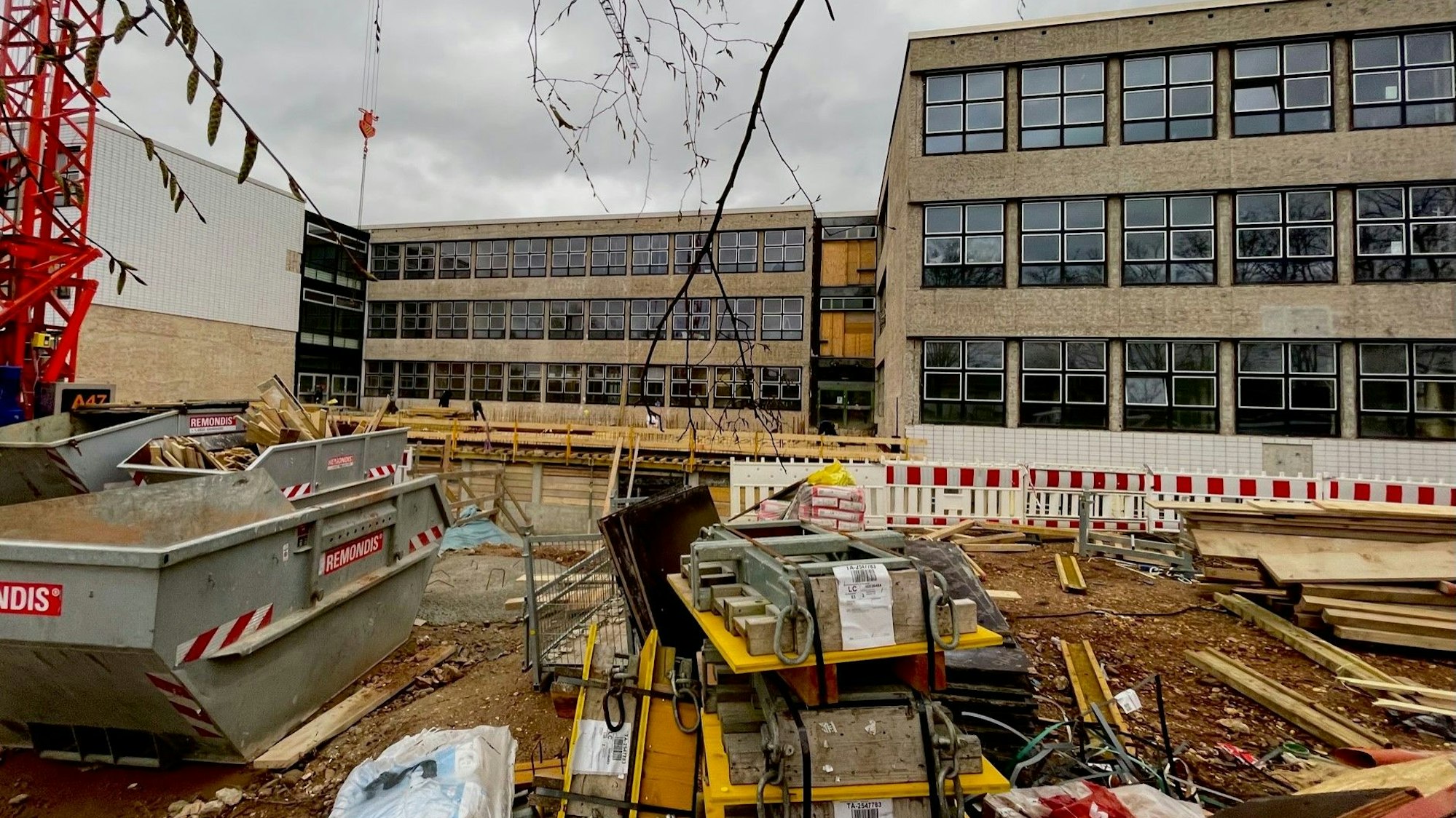 Blick auf die Baustelle des Schulzentrums. Ein Container und Schutt stehen vor dem Gebäude.