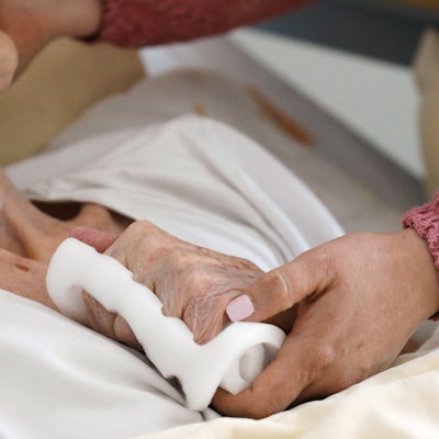 Eine Pflegeschwester hält die Hand einer alten Heimbewohnerin im Altenzentrum Luisenhaus.