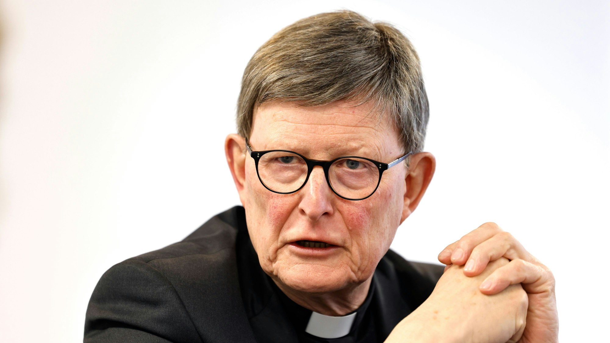 Man sieht Woelki, wie er die Hände zusammenlegt und redet.