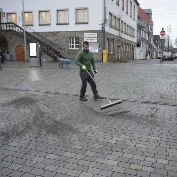 Ein Mitarbeiter der Firma G.W.D. verfugt die Grauwackesteine auf dem Marktplatz neu.