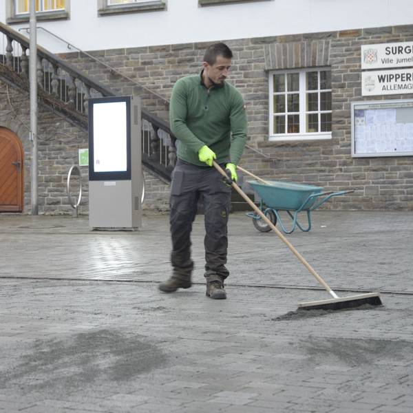 Ein Mitarbeiter der Firma G.W.D. verfugt die Grauwackesteine auf dem Marktplatz neu.