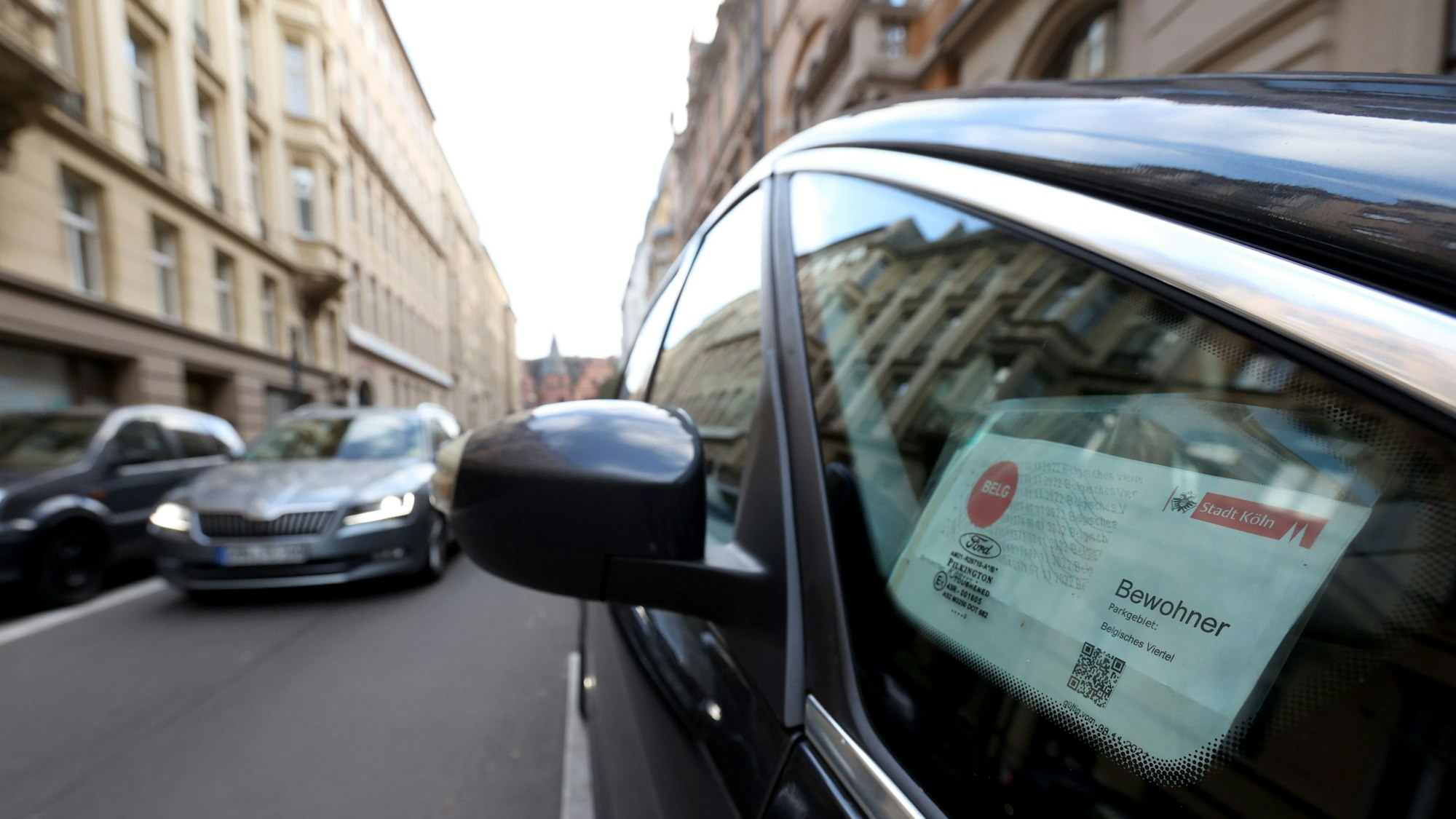 In einem Autofenster hängt ein Anwohnerparkausweis für das Belgische Viertel in Köln