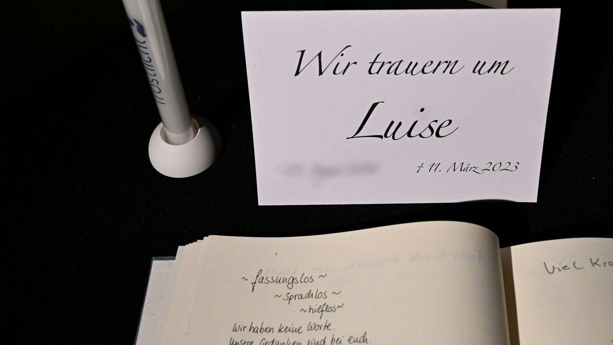 Man sieht die Trauerkarte samt Kondolenzbuch und einen Stift.