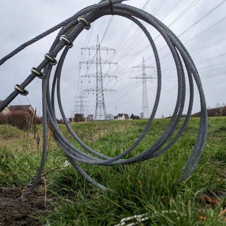 In Hürth beschweren sich Anwohner über peitschende Geräusche von den im Bau befindlichen Hochspannungsmasten. Das Foto zeigt Stahlkabel und im Hintergrund die Masten.