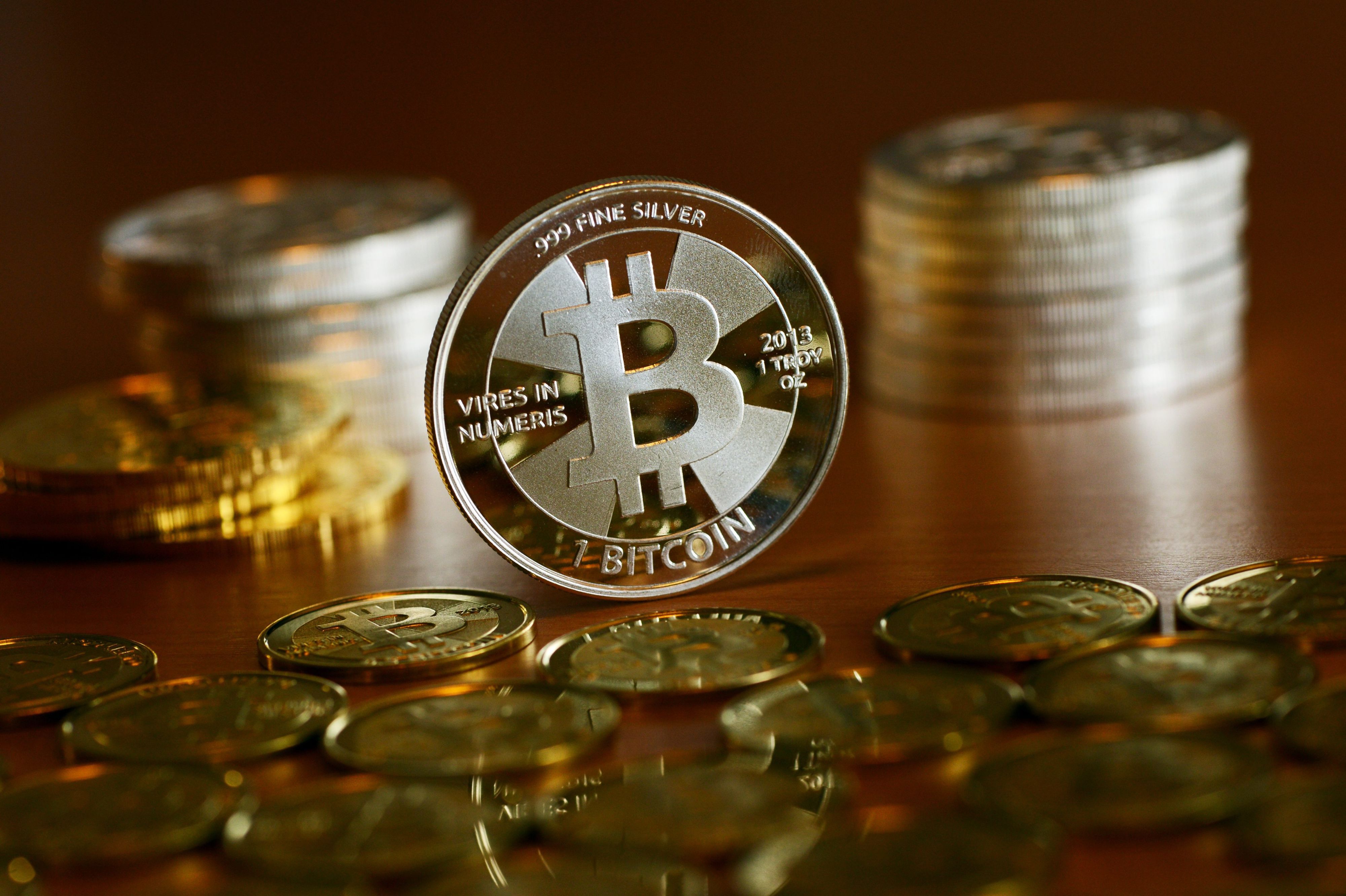 Münzen mit dem Aufdruck „Bitcoin“ stehen und liegen auf einem Tisch. (Symbolbild)