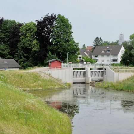 Hinter dem Hochwasserbecken und Schleuse Kippemühle in Bergisch Gladbach-Gronau liegen Häuser.