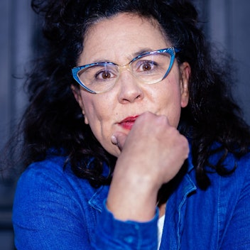 Ramona Schukraft alias Sybille Bullatschek trägt einen blauen Blazer und eine blaue Brille.