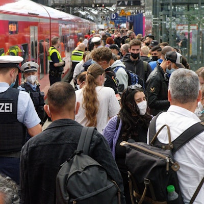 Polizei und Mitarbeiter der Deutschen Bahn weisen Reisenden auf einem überfülltem Bahnsteig im Hauptbahnhof den Weg.