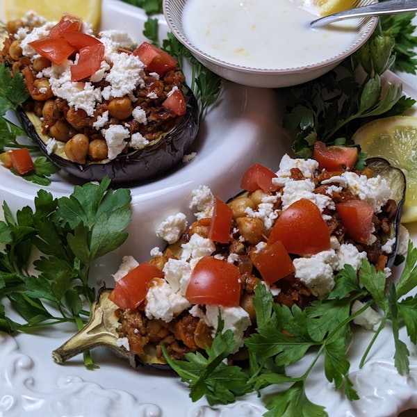 Man sieht die gefüllte Aubergine, daneben eine Schale mit dem Dip.