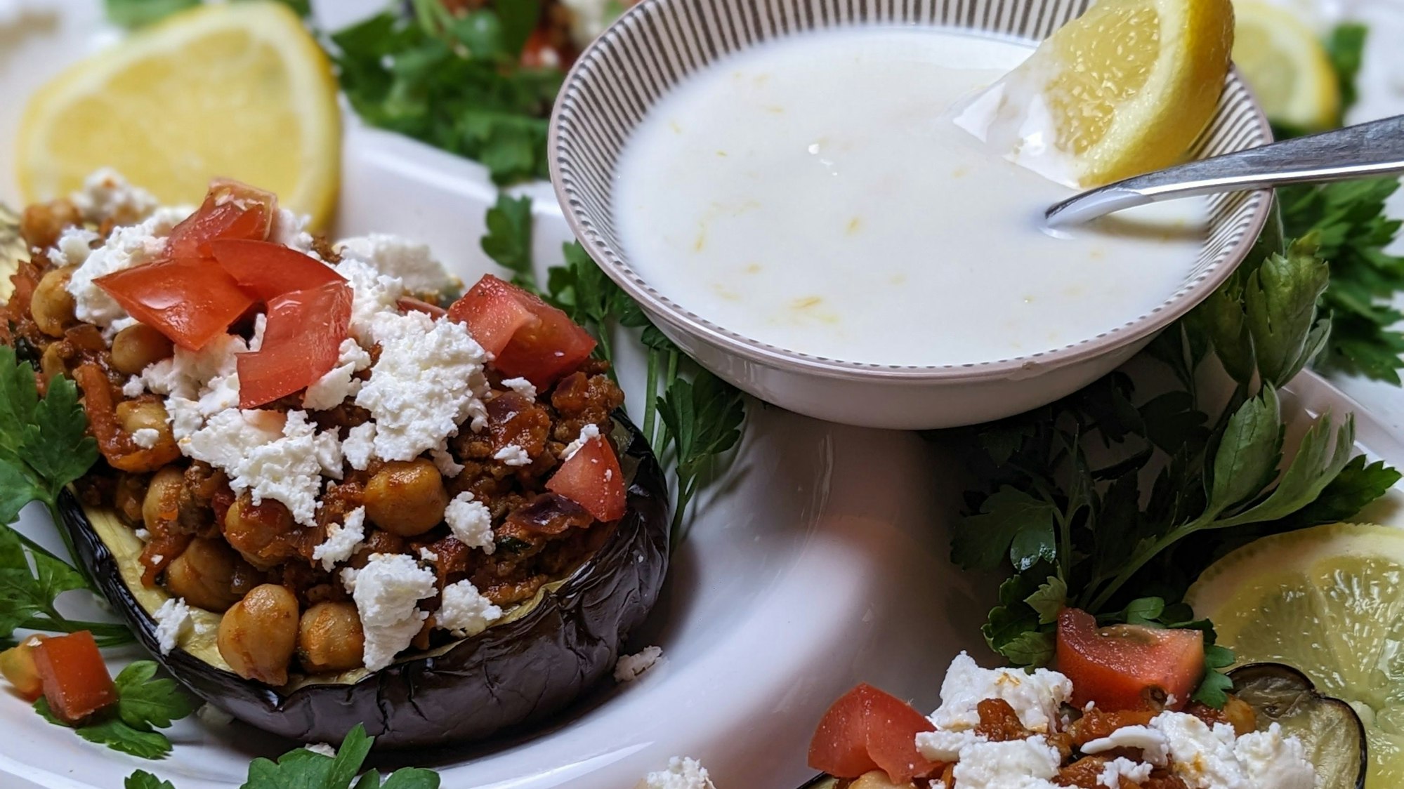 Man sieht die gefüllte Aubergine, daneben eine Schale mit dem Dip.