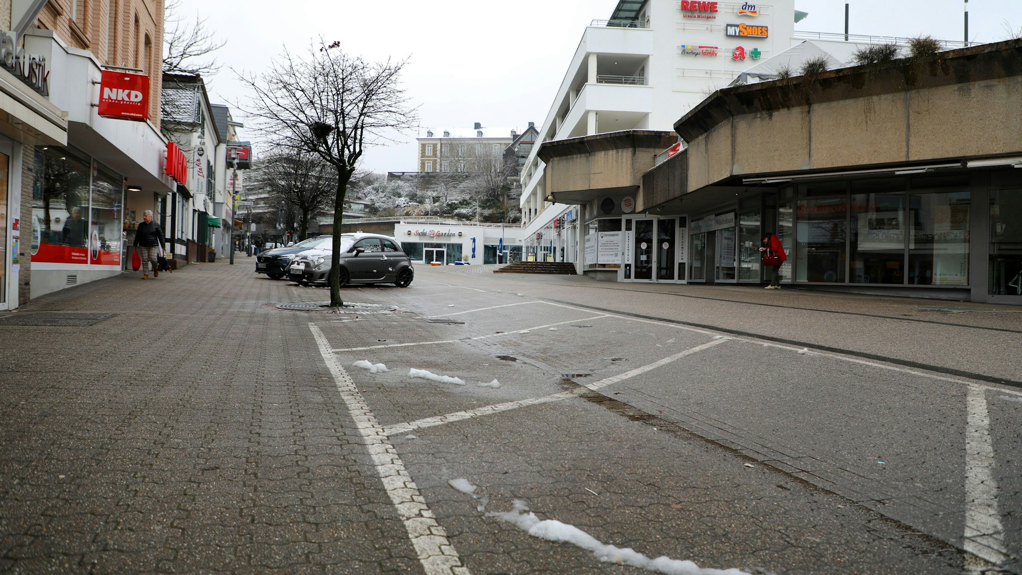 Im Vordergrund befinden sich mehrere freie Parktaschen, im Hintergrund sind die Schlossgalerie an der Schloßstraße sowie am Horizont das Schloss Bensberg zu sehen.