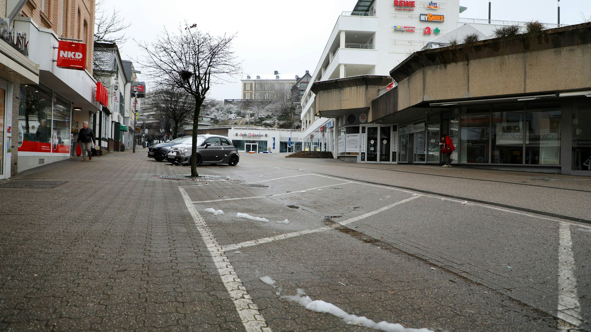 Im Vordergrund befinden sich mehrere freie Parktaschen, im Hintergrund sind die Schlossgalerie an der Schloßstraße sowie am Horizont das Schloss Bensberg zu sehen.