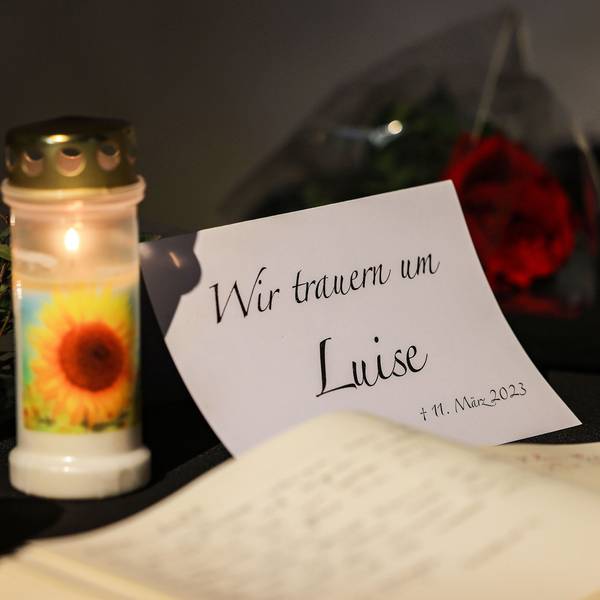 Zwei Kerzen und eine Trauerkarte stehen auf einem Tisch.