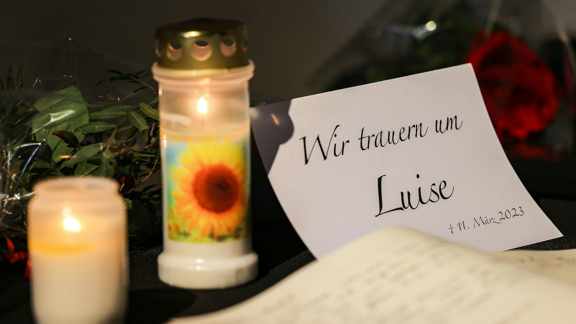 Zwei Kerzen und eine Trauerkarte stehen auf einem Tisch.