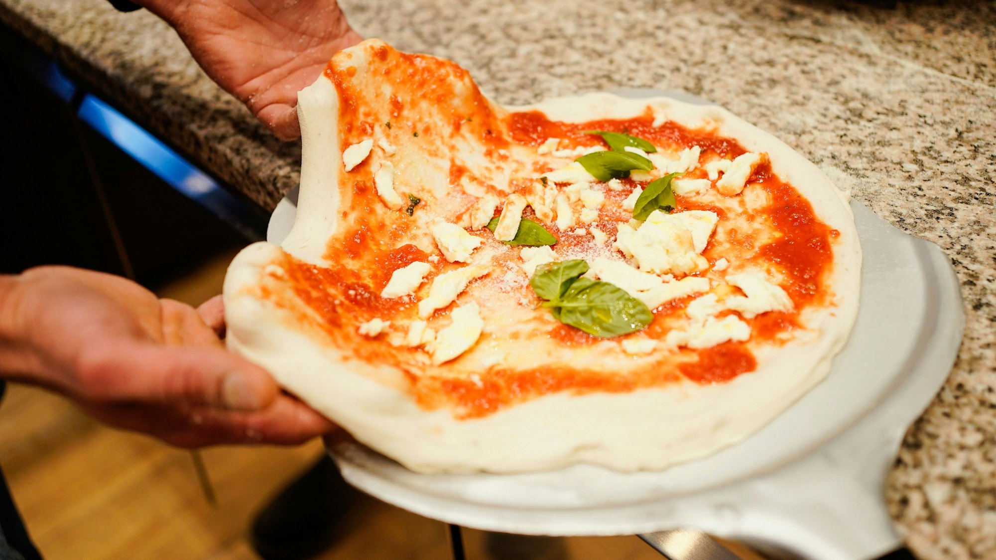 Eine noch ungebackene Pizza auf einem Ofenschieber