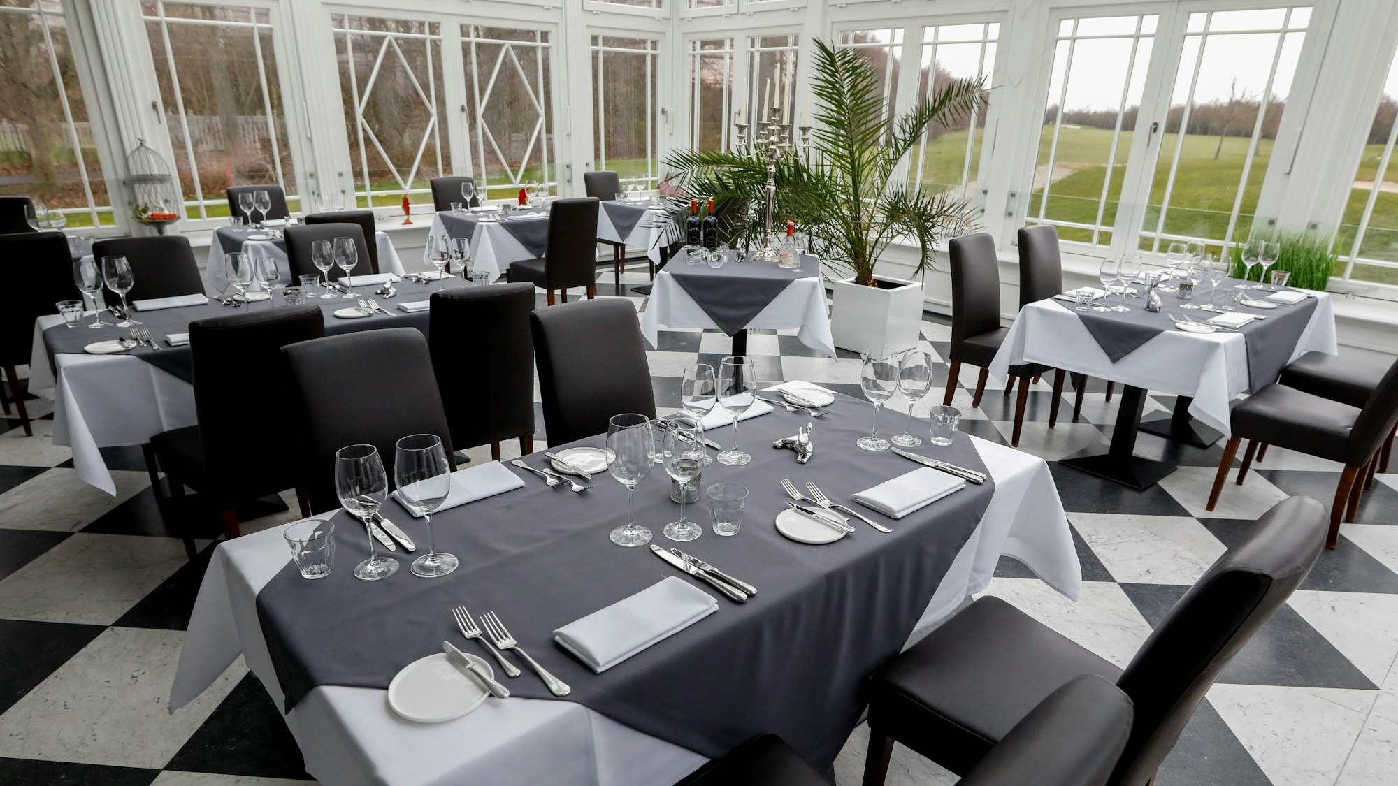 Schwarz-weißer Fußboden, heller Gastraum mit Blick ins Grüne