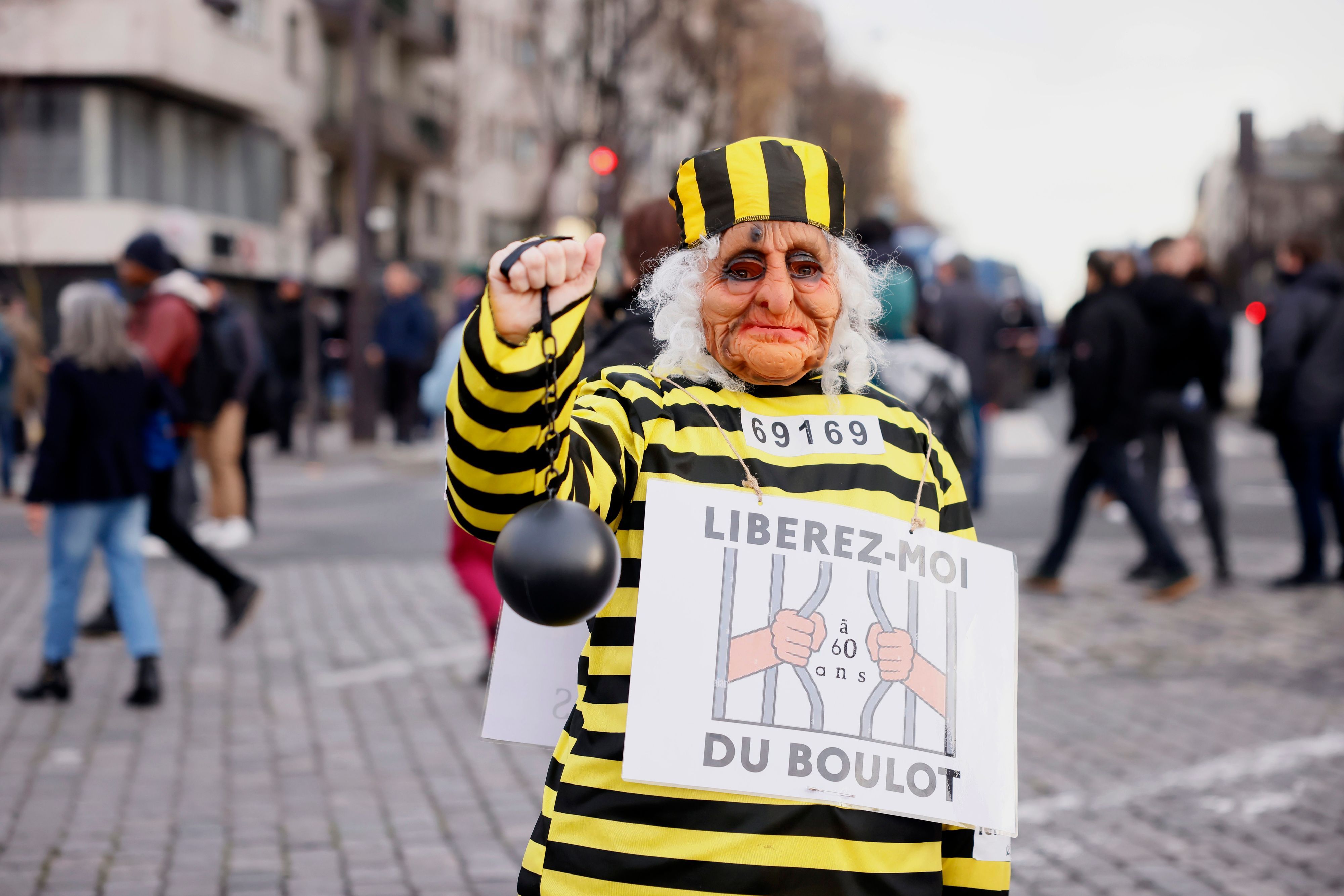 Ein Demonstrant trägt während einer Demonstration ein Plakat mit der Aufschrift „Befreie mich mit 60 von der Arbeit“.