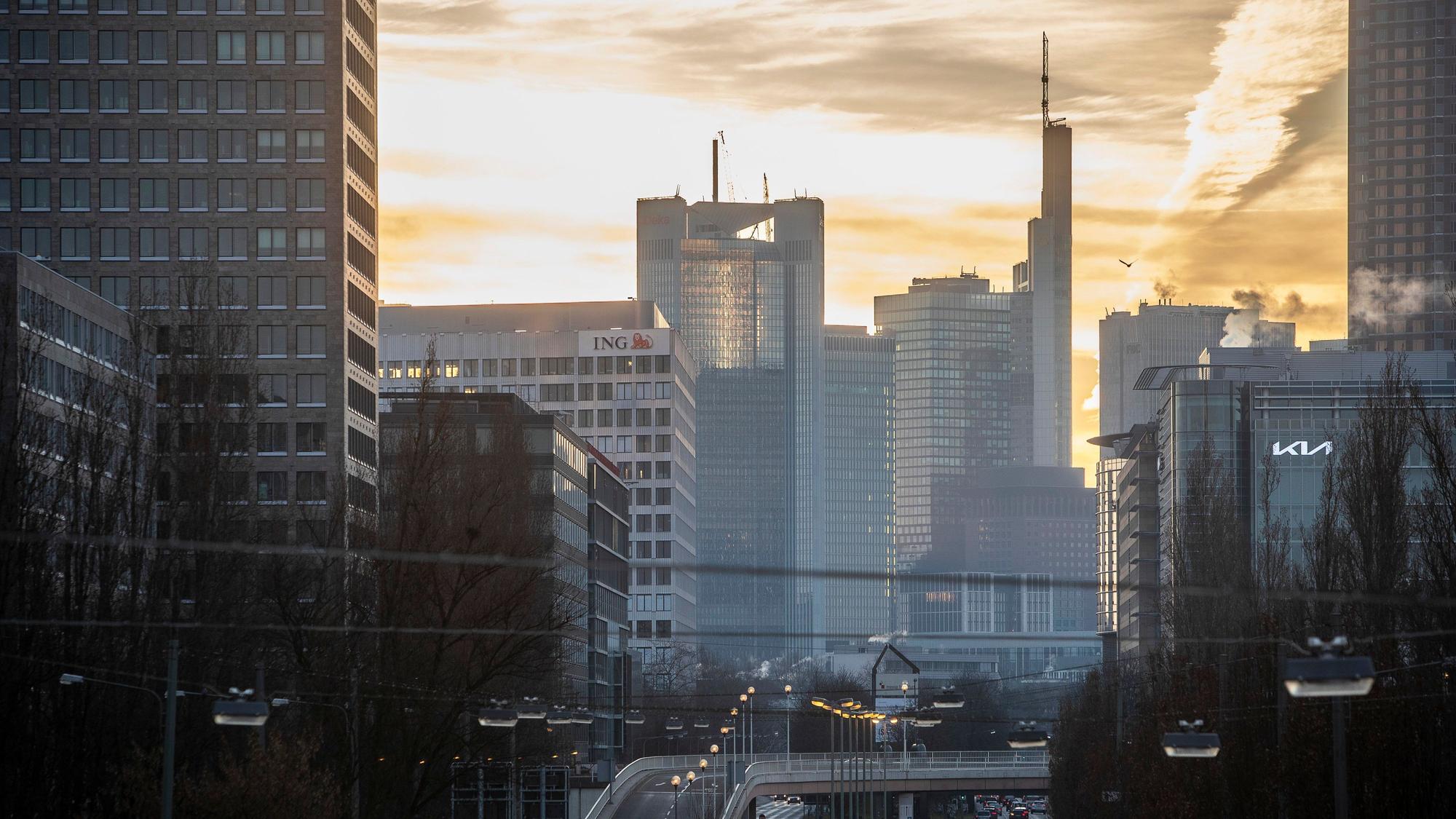 Man sieht die Skyline des Frankfurter Bankenviertels gegen den Sonnenaufgang.