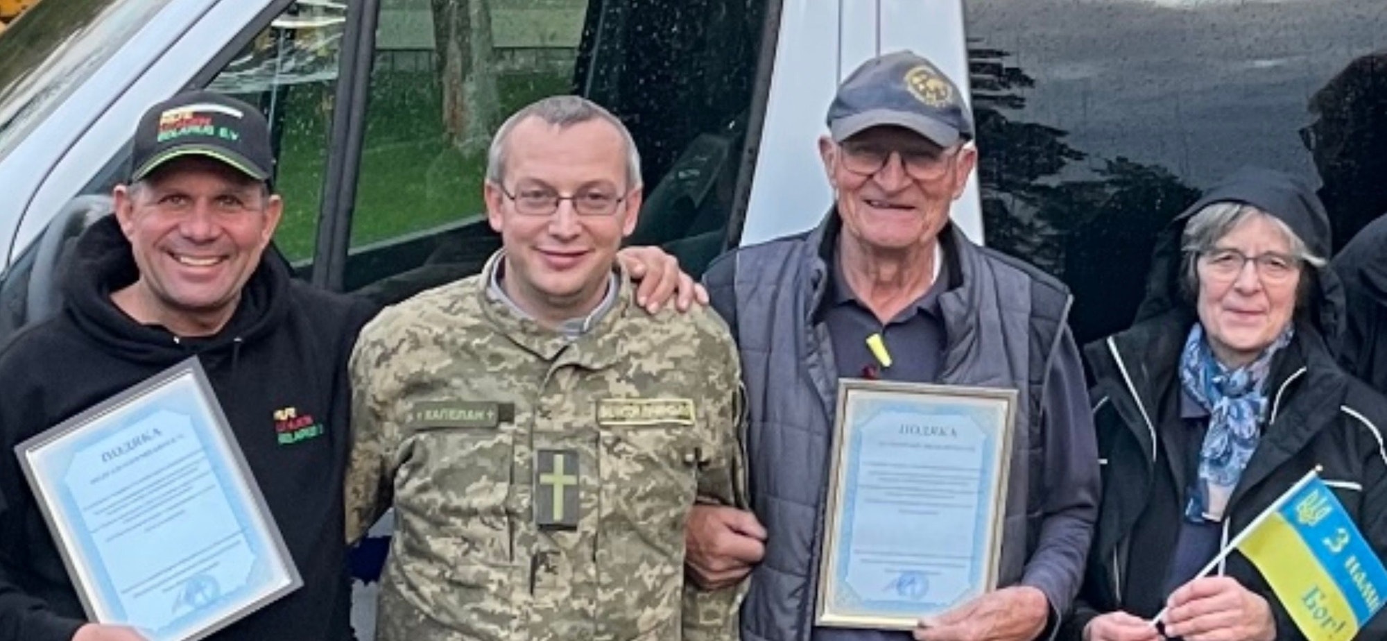 Hilfstransporteure aus Overath und Bergisch Gladbach stehen mit einem Militärseelsorger vor einem Hilfstransporter.