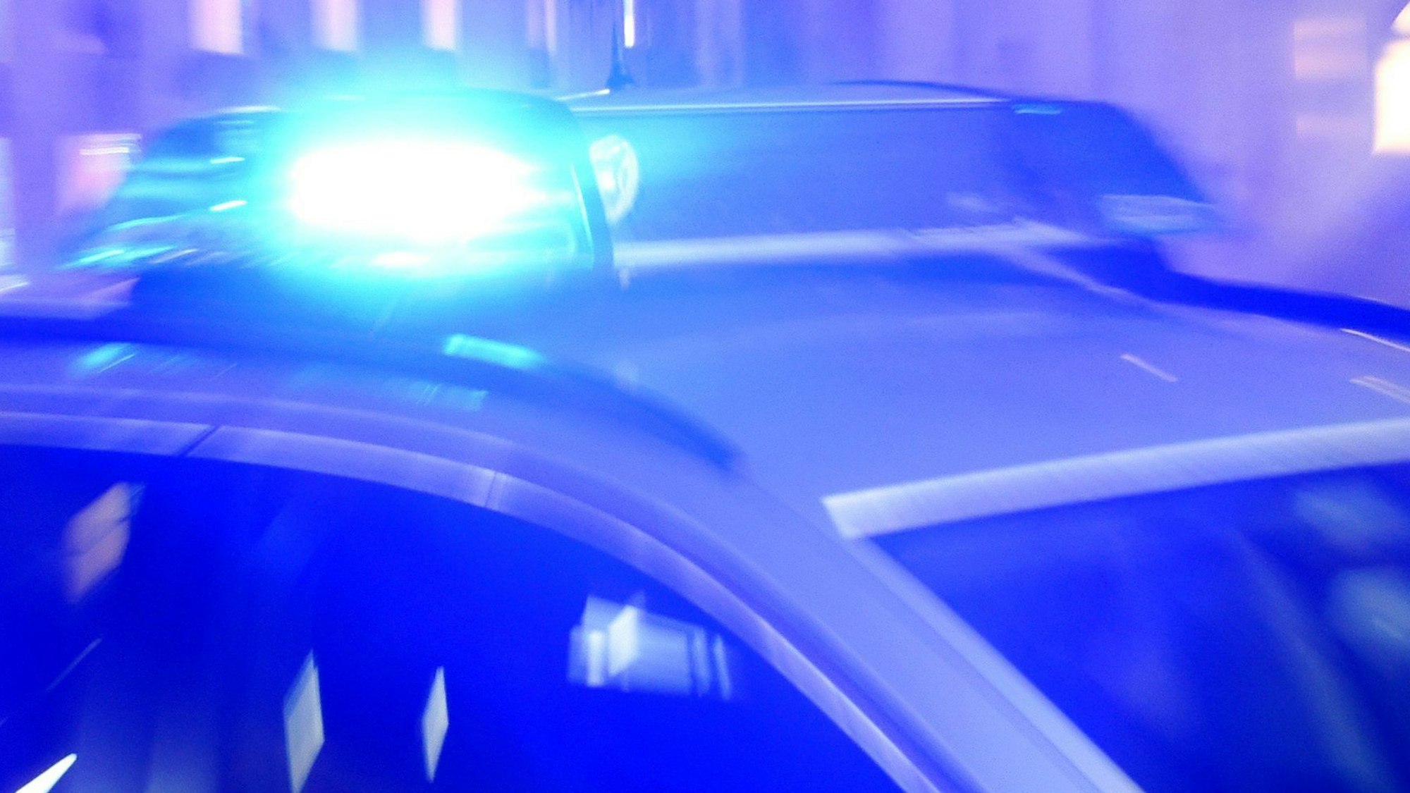 Ein Streifenwagen der Polizei steht mit eingeschaltetem Blaulicht auf der Straße.