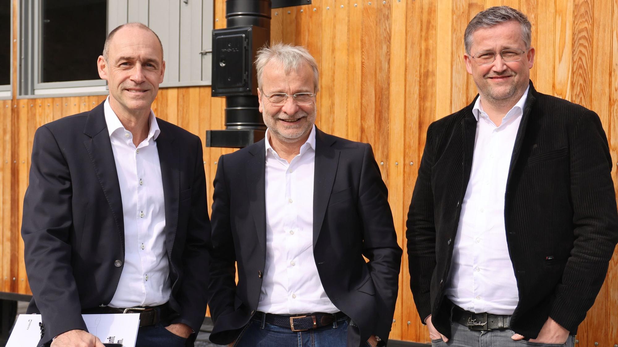 Gruppenfoto mit drei Herren vor einem Bauwagen.