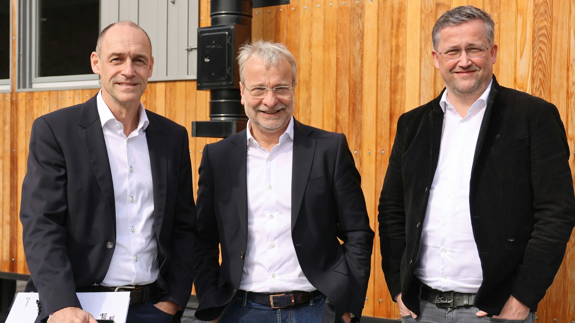 Gruppenfoto mit drei Herren vor einem Bauwagen.