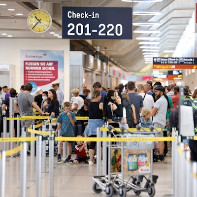 25.06.2022, Nordrhein-Westfalen, Köln: Passagiere stehen am Samstag Vormittag in einer Schlange von mehreren hundert Metern für die Sicherheitskontrolle am Flughafen Köln Bonn an.