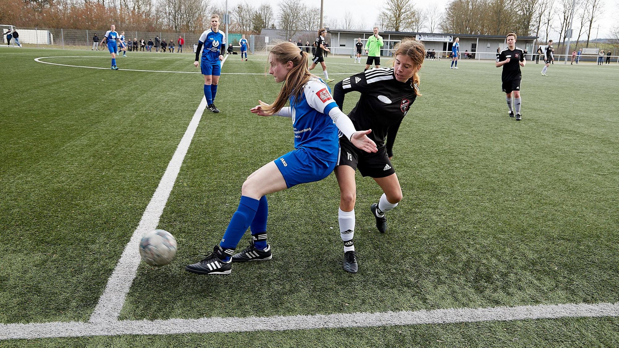 Das Bild zwei Fußballerinnen im Kampf um den Ball an der Außenlinie.