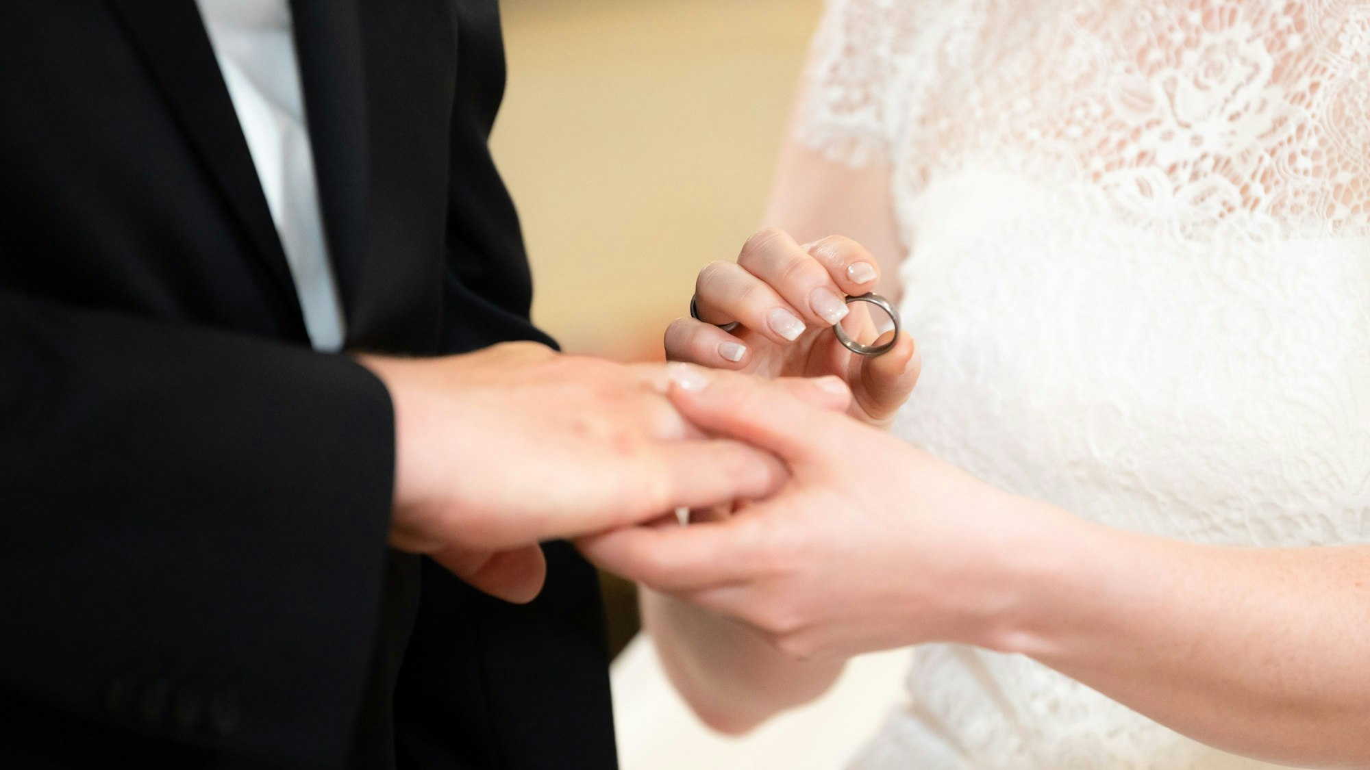 Ein Brautpaar steckt sich während der Trauung in der Kirche die Ringe an.