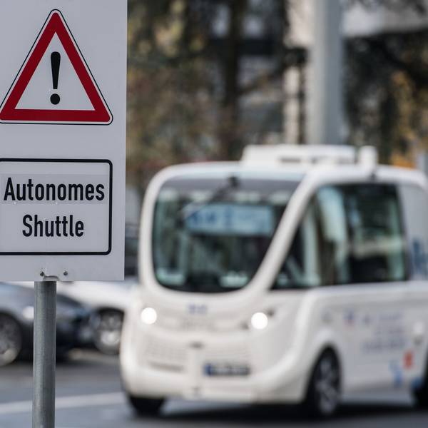 Ein autonomes Shuttle fährt hinter einem Warnschild her, das auf dieses hinweist.
