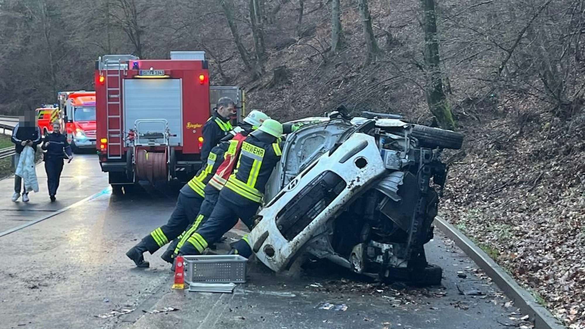 Feuerwehrleute richten ein Auto auf.