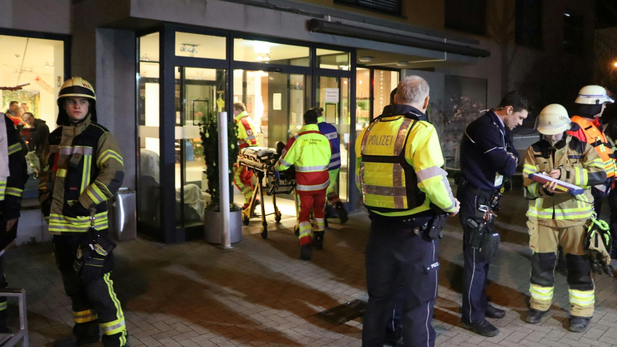 Einsatzkräfte stehen vor dem Eingang des Seniorenwohnheimes.
