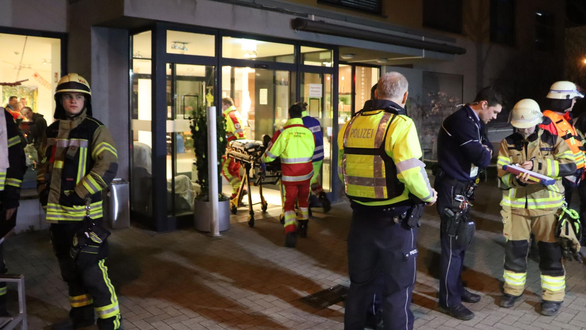 Einsatzkräfte stehen vor dem Eingang des Seniorenwohnheimes.