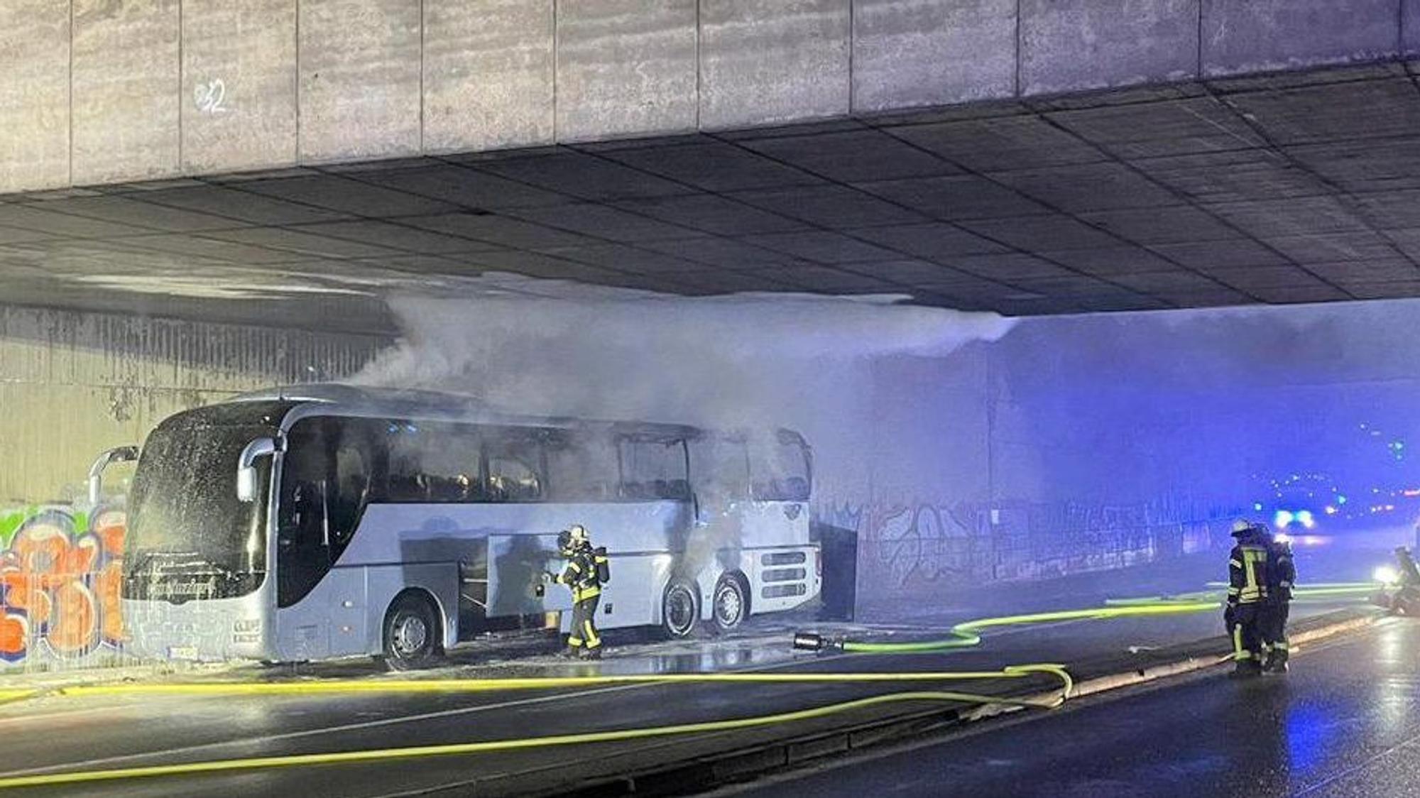 Ein Reisebus steht unter einer Brücke. Qualm steigt aus dem Bus auf.