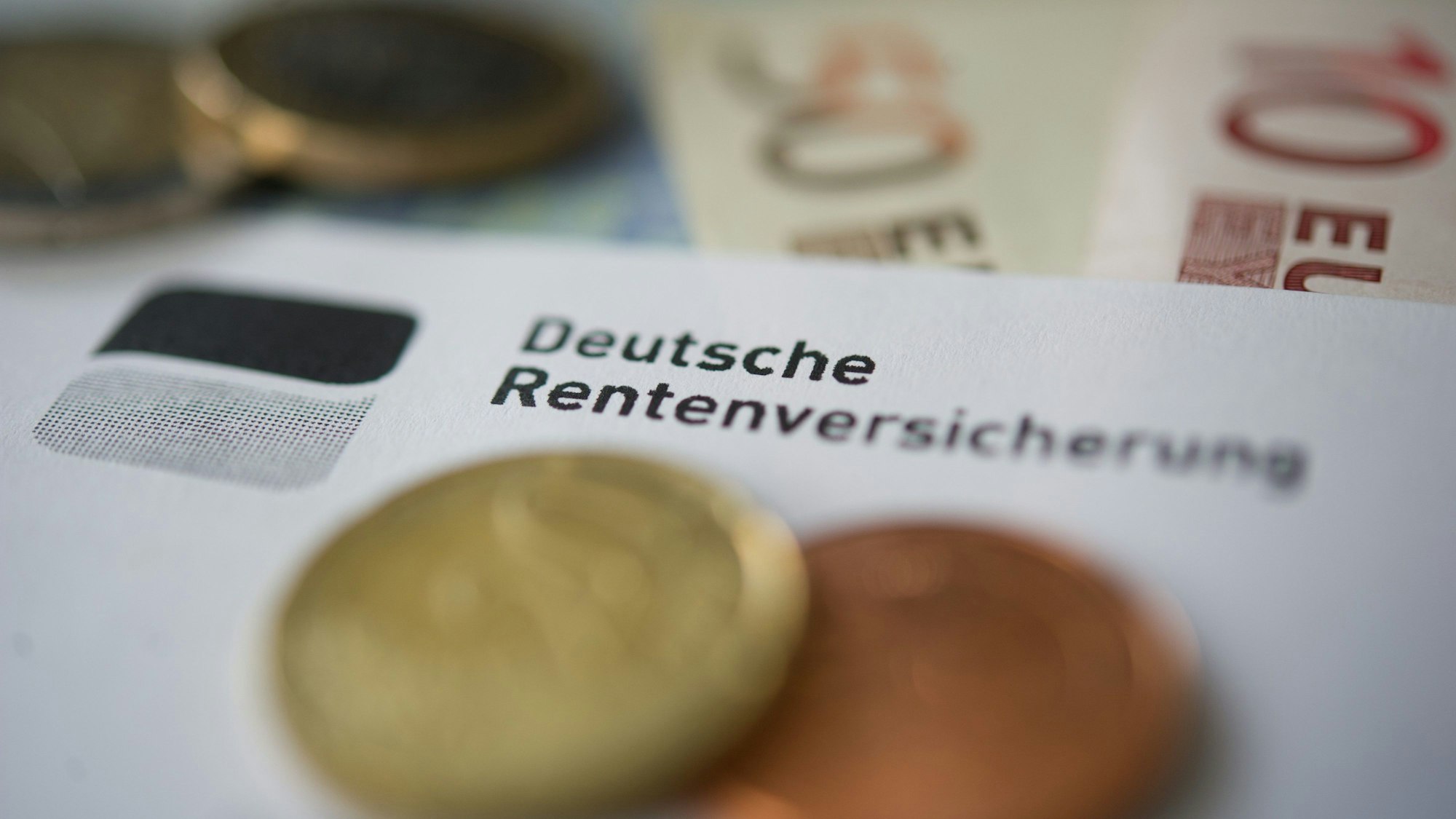 Münzen und Geldscheine liegen neben einem Schreiben mit der Aufschrift «Deutsche Rentenversicherung».