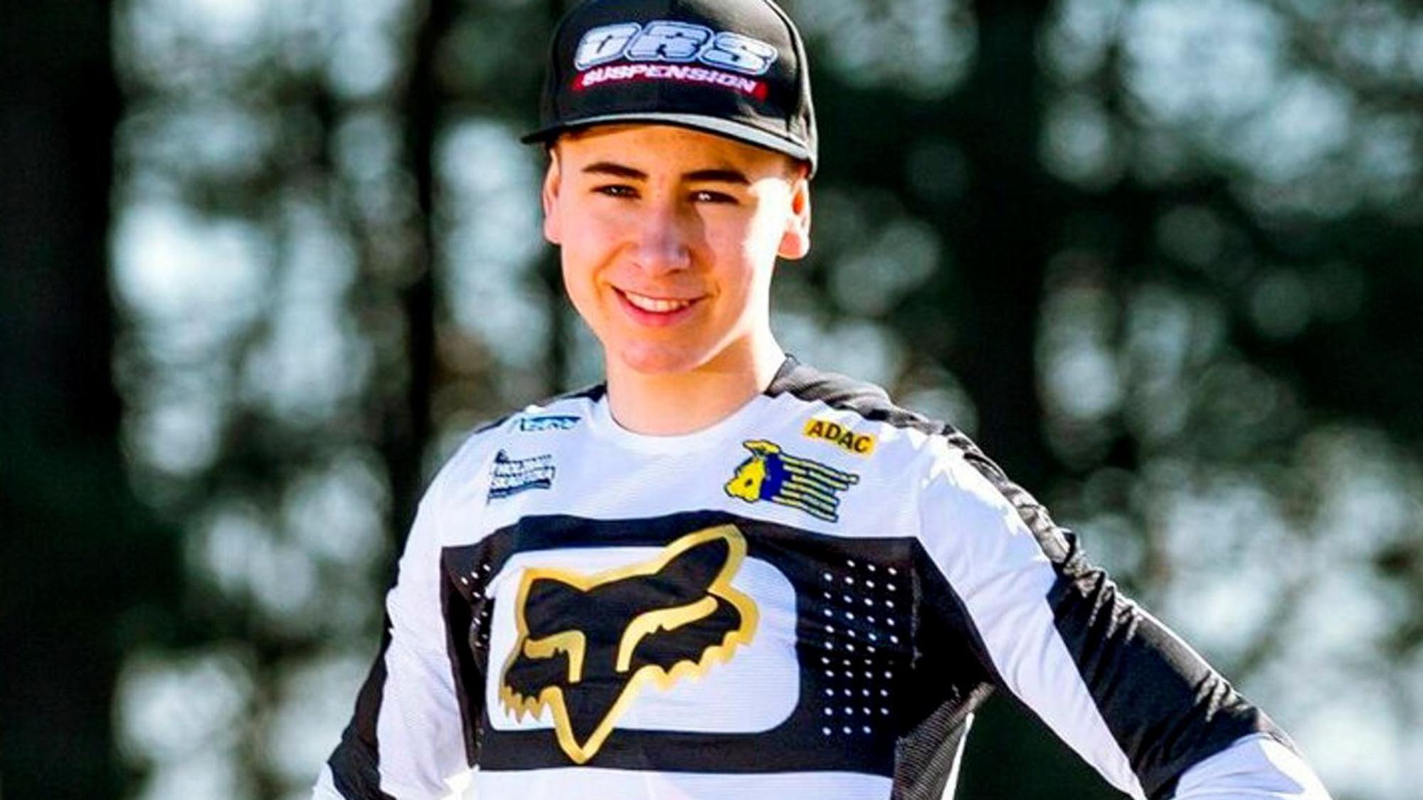 Jan Krug steht mit den Händen in den Hüften vor die Kamera und trägt seinen Rennanzug