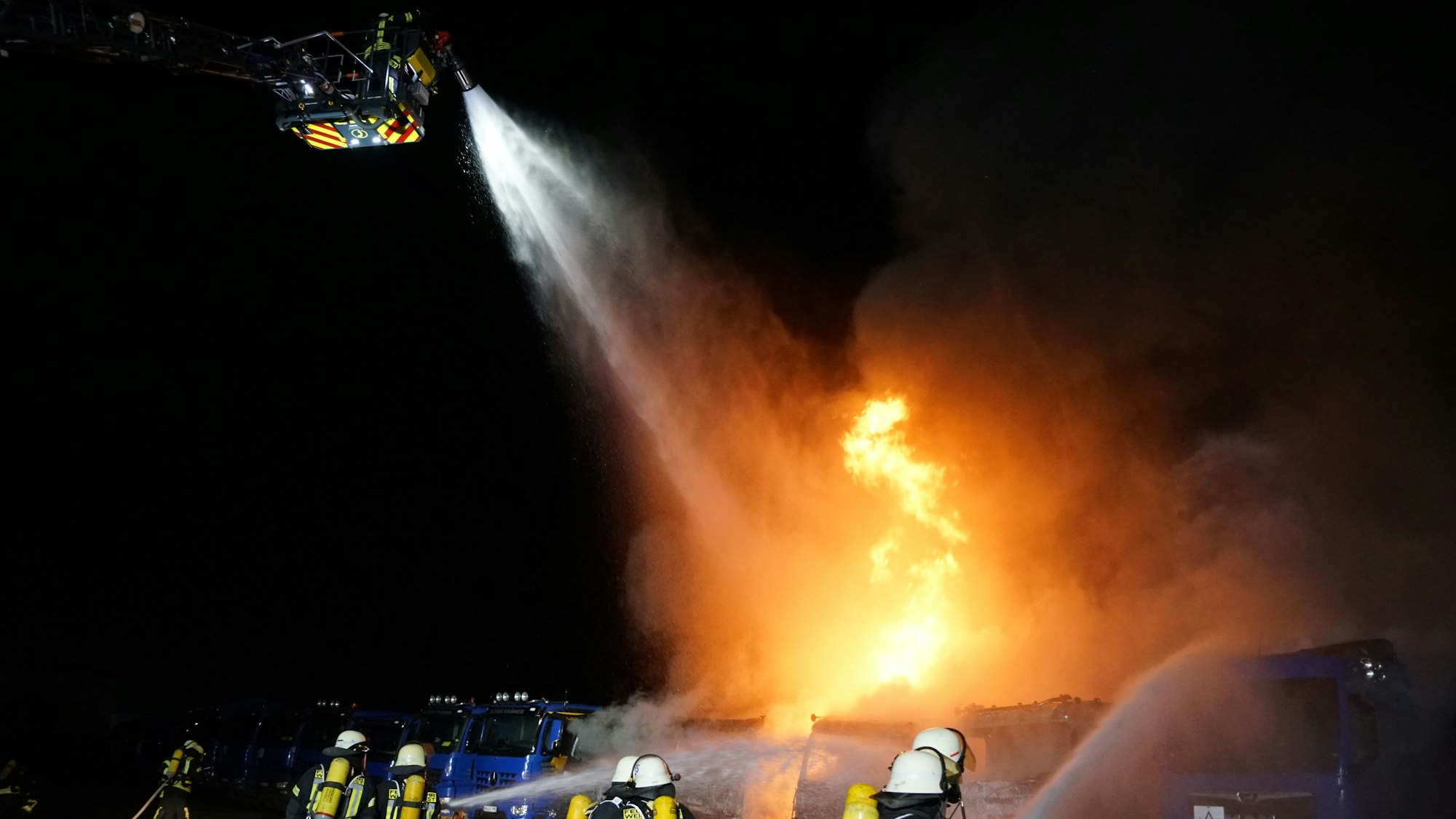 Aus dem Korb der Drehleiter bekämpfen Feuerwehrleute die Flammen .