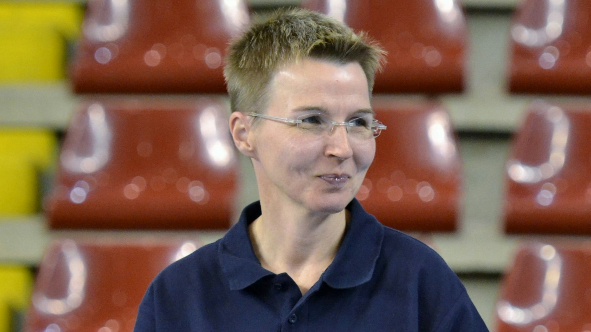 Conny blickt in einem dunkelblauen Poloshirt lächelnd zur Seite.