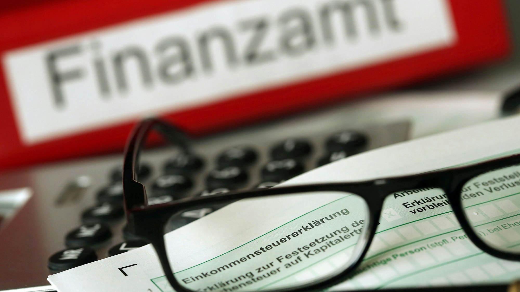 Auf einem Vordruck für die Steuererklärung liegen Stift und eine Brille.+++