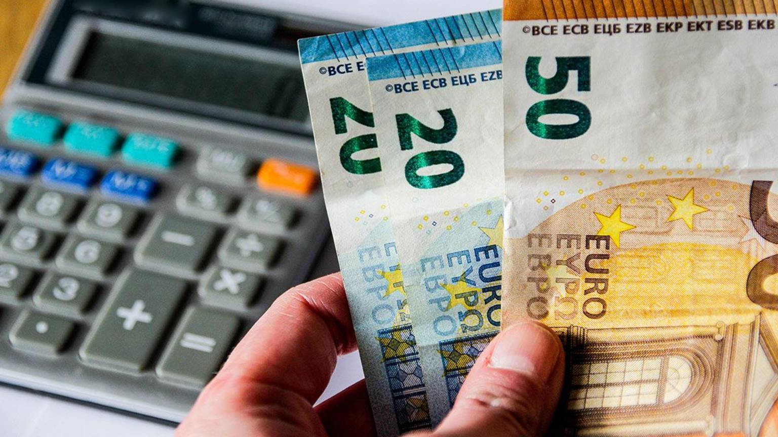 Taschenrechner und Geldscheine in der Hand