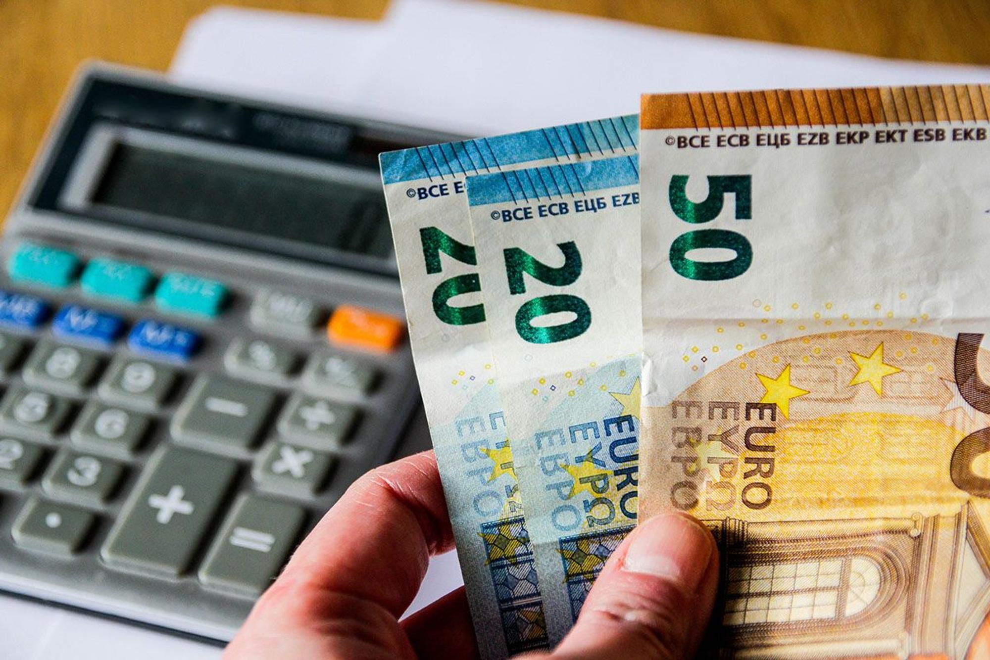 Taschenrechner und Geldscheine in der Hand