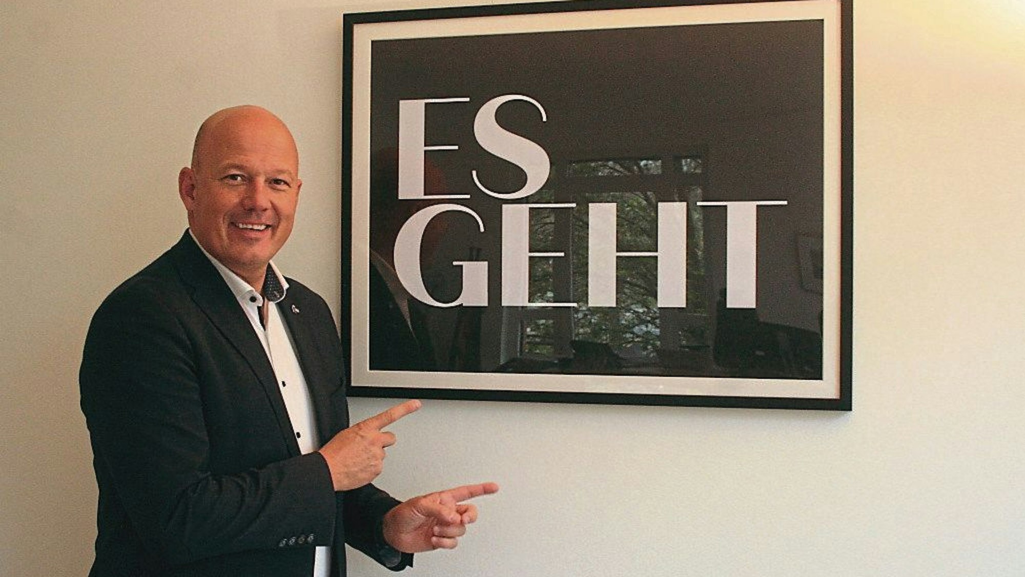 Das Foto zeigt Landrat Frank Rock. In einem Bilderrahmen ist sein Motto festgehalten: „Es geht.“