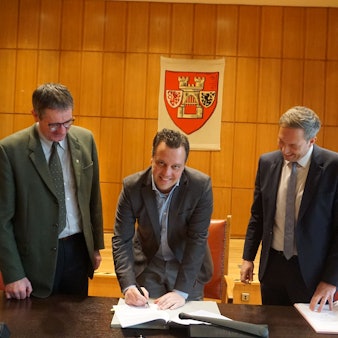 Matthias Laufer, Geschäftsführer der Friedwald GmbH (v.l.), Bürgermeister Sacha Reichelt und Forstamtsleiter Christoph Böltz unterschreiben den Kooperationsvertrag zur Anlage eines Friedwaldes im Hardtwald in Euskirchen.