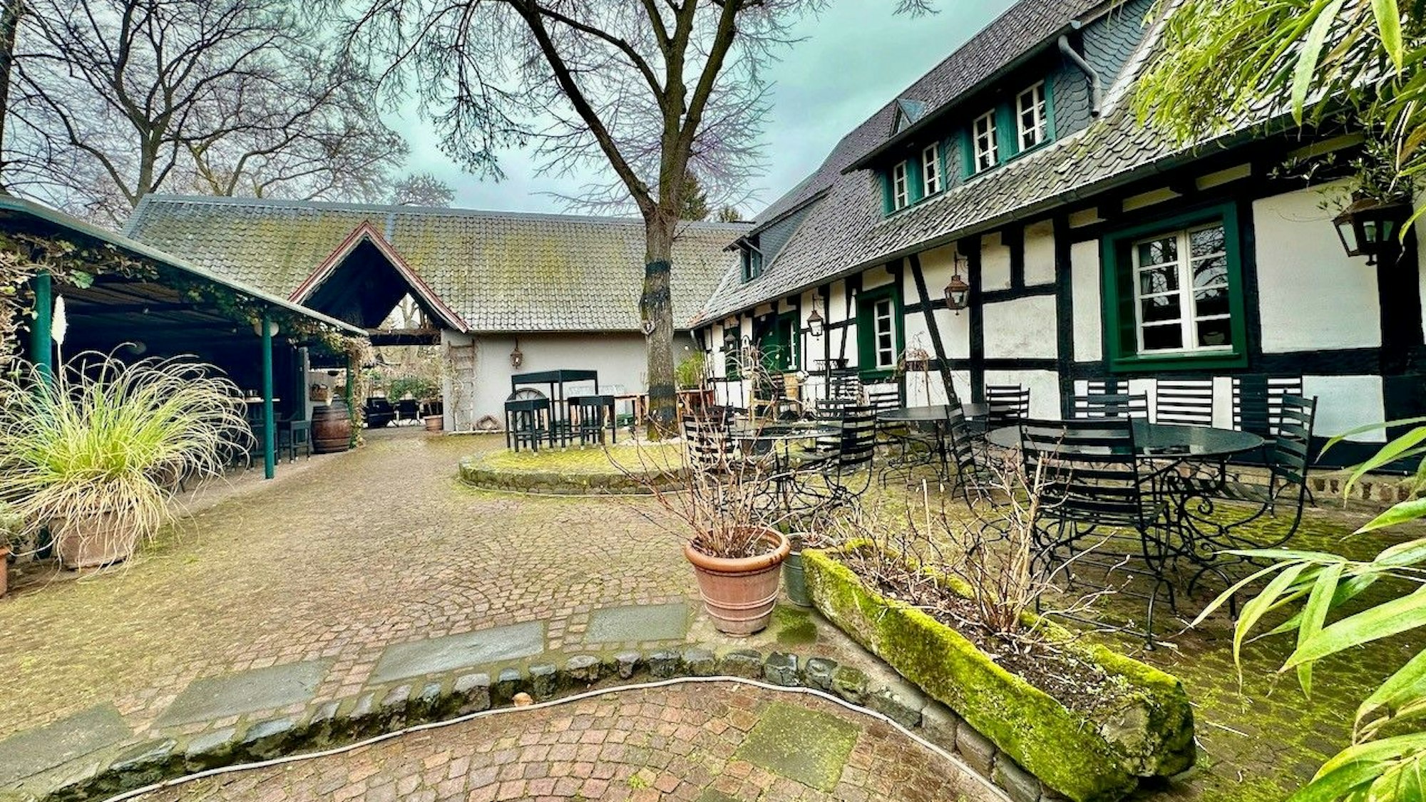 Der Innenhof des Geländes mit Blumenkübeln, Tischen und Stühlen.