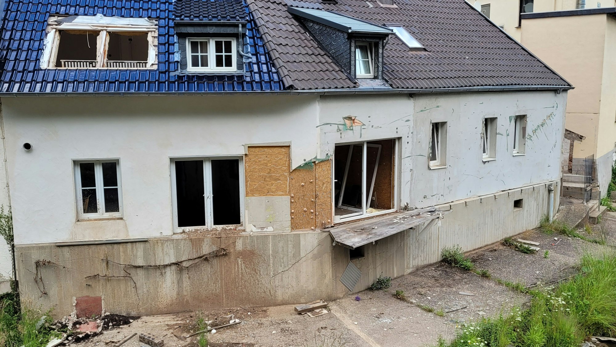 Das Bild zeigt ein Fluthaus mit kaputten Fenstern und Türen.